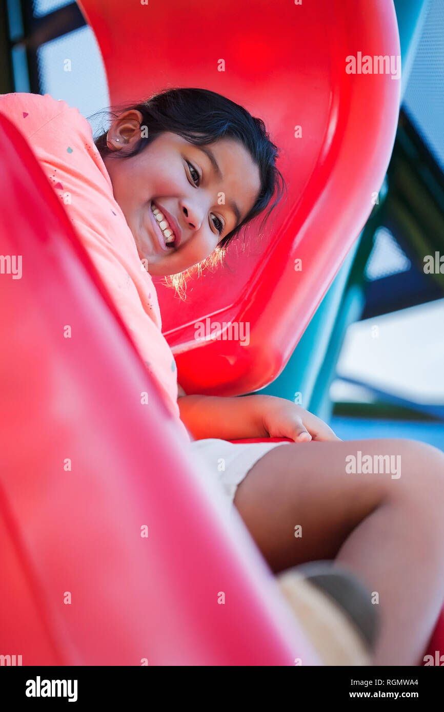 Muchacha con nervioso y excitado la expresión facial que se sujetan a un playground diapositiva antes de dejar ir. Foto de stock