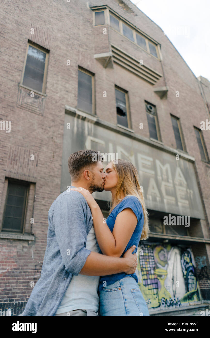 Afectuoso joven pareja besándose en la ciudad, en frente de un cine Foto de stock