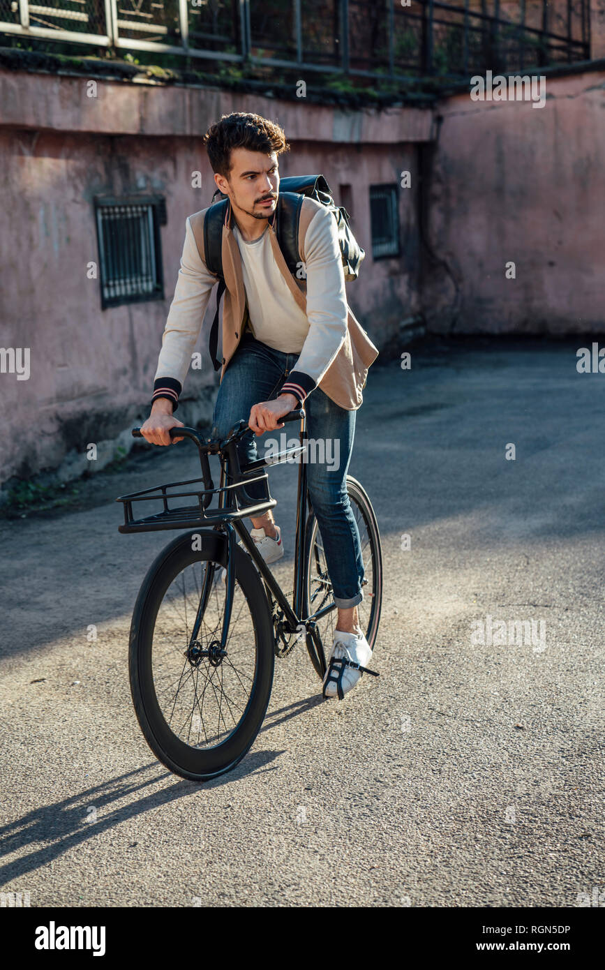 Joven con mochila montando bicicleta fixie suburbano en la ciudad  Fotografía de stock - Alamy