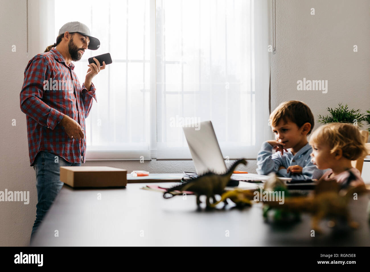 Padre grabando un archivo de audio, mientras los niños están utilizando su ordenador portátil Foto de stock