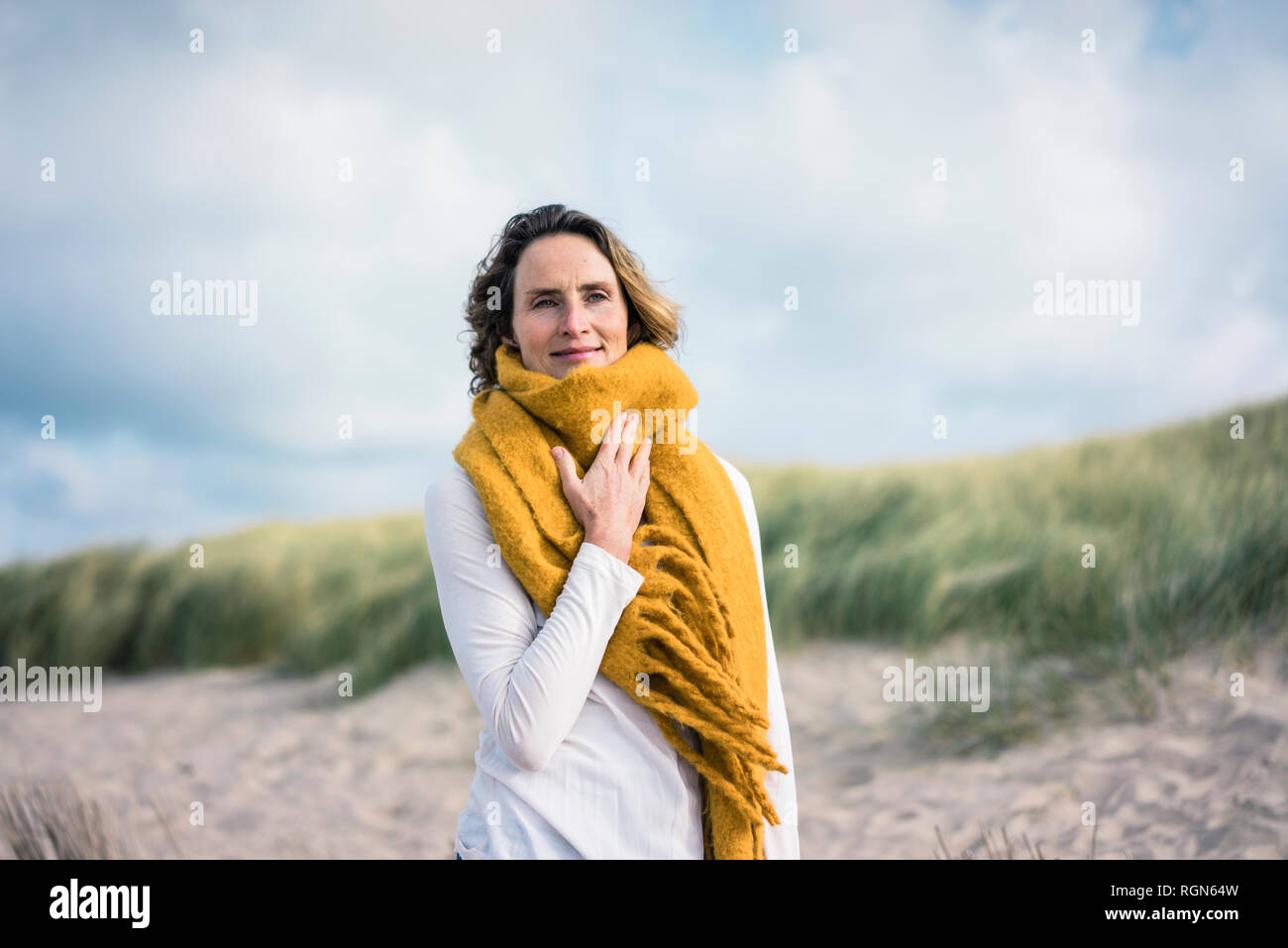 Mujer madura, relajándose en las dunas, disfrutando del viento Foto de stock