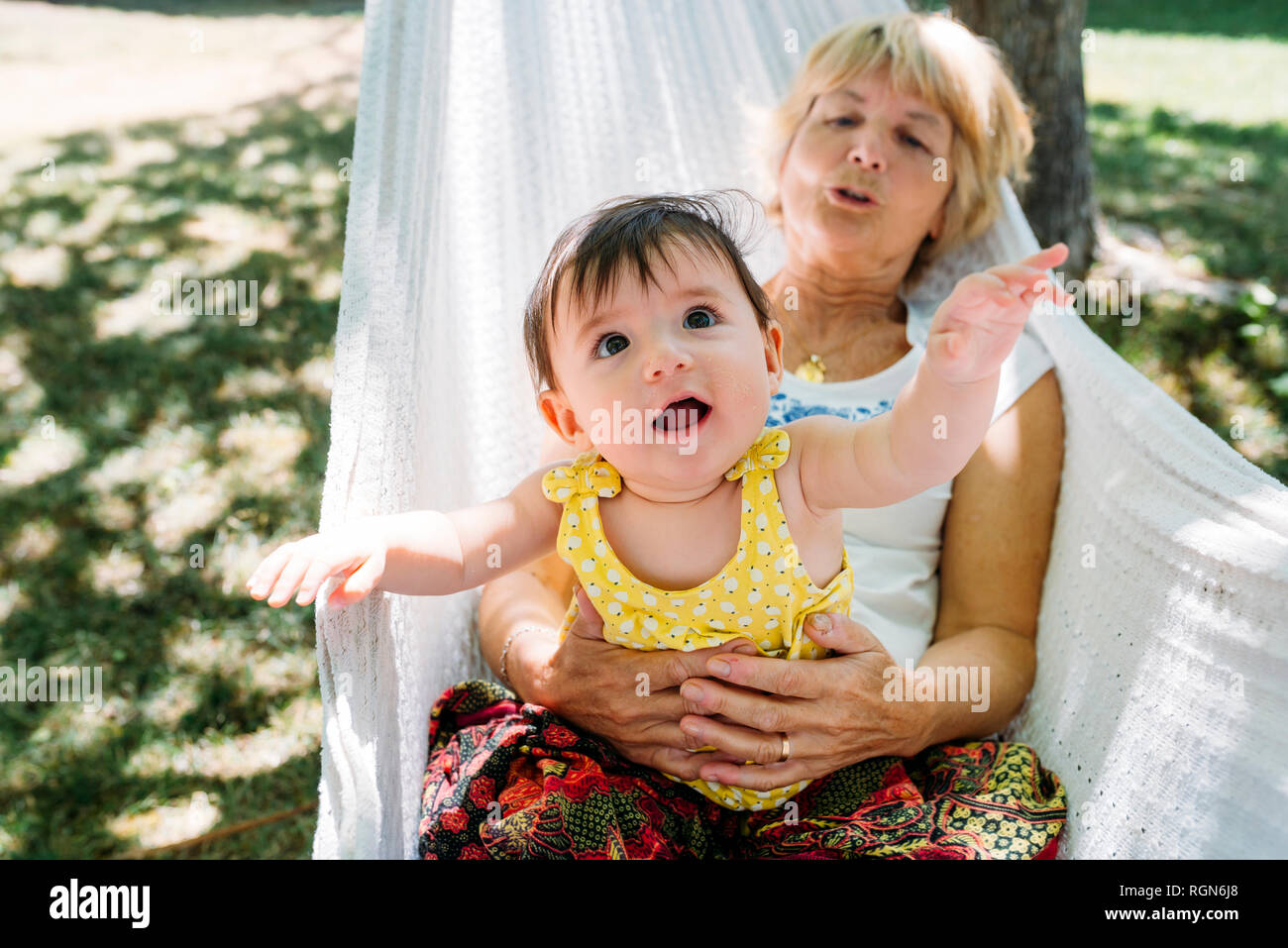 España, la abuela y el bebé relajarse en una hamaca en el jardín en el verano Foto de stock