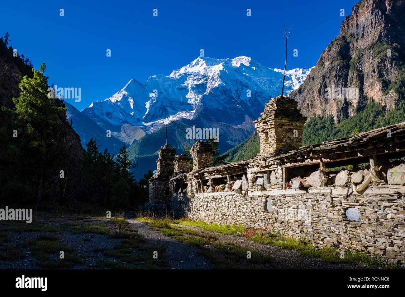 Gran pared de Mani en el valle de Marsyangdi superior, la nieve cubrió la cumbre de Annapurna 2 en la distancia Foto de stock