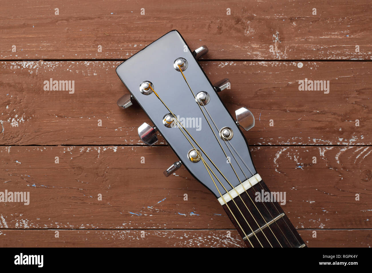 Instrumento musical - clavijero peghead guitarra acústica negra sobre un  fondo de madera Fotografía de stock - Alamy