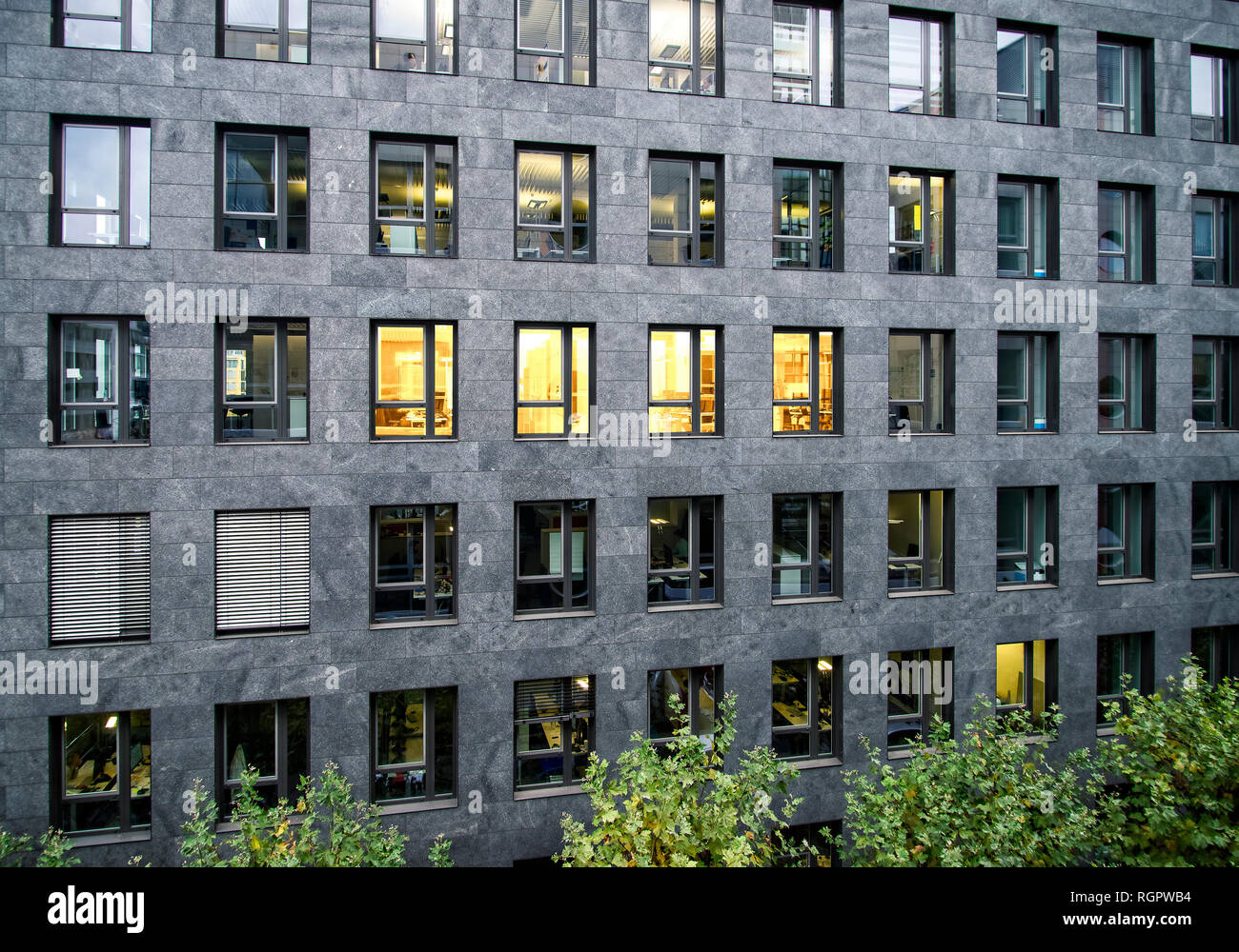Fachada de un edificio de oficinas con algunas ventanas iluminadas Foto de stock