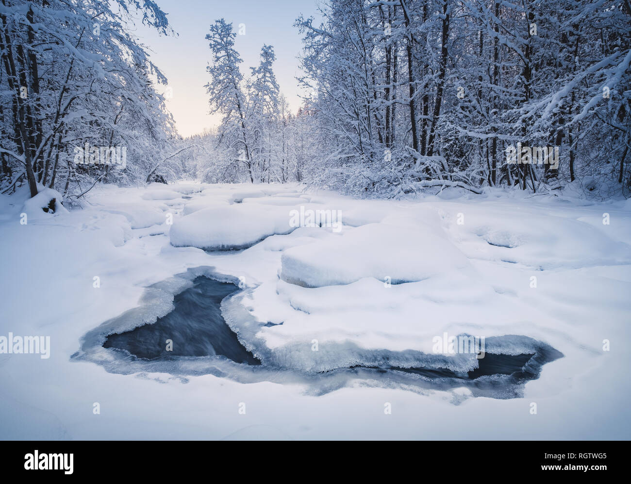 Pintoresco paisaje de invierno con el flujo del río y la luz de la mañana en Finlandia Foto de stock