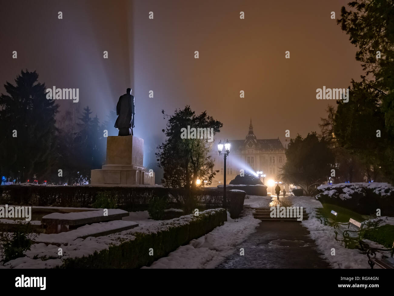 Escena nocturna al aire libre en el parque principal de Satu Mare con misteriosas luces por Vasile Lucaciu estatua histórica, en Rumania Foto de stock