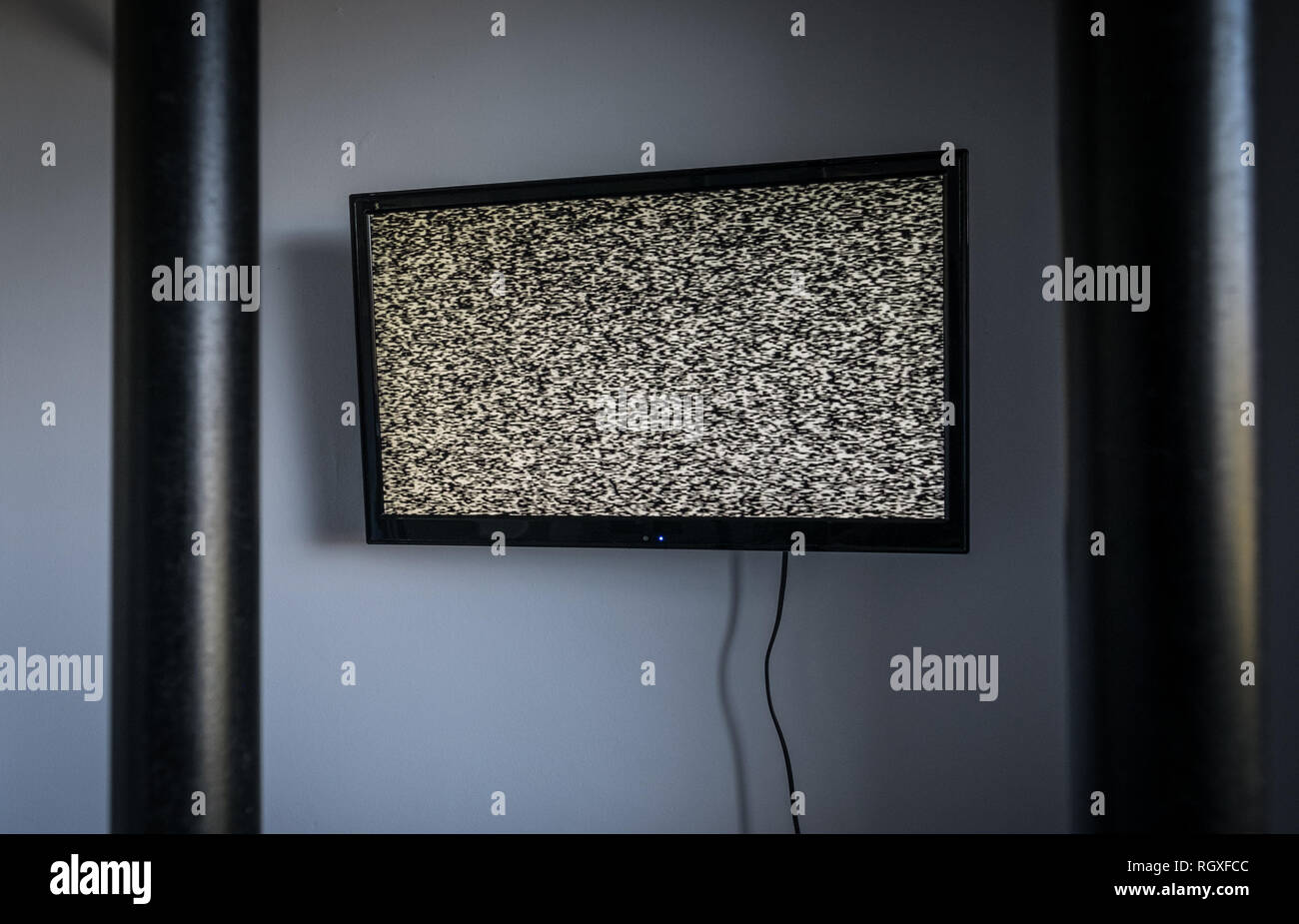 Un televisor en la pared de una celda de prisión tras las rejas Foto de stock