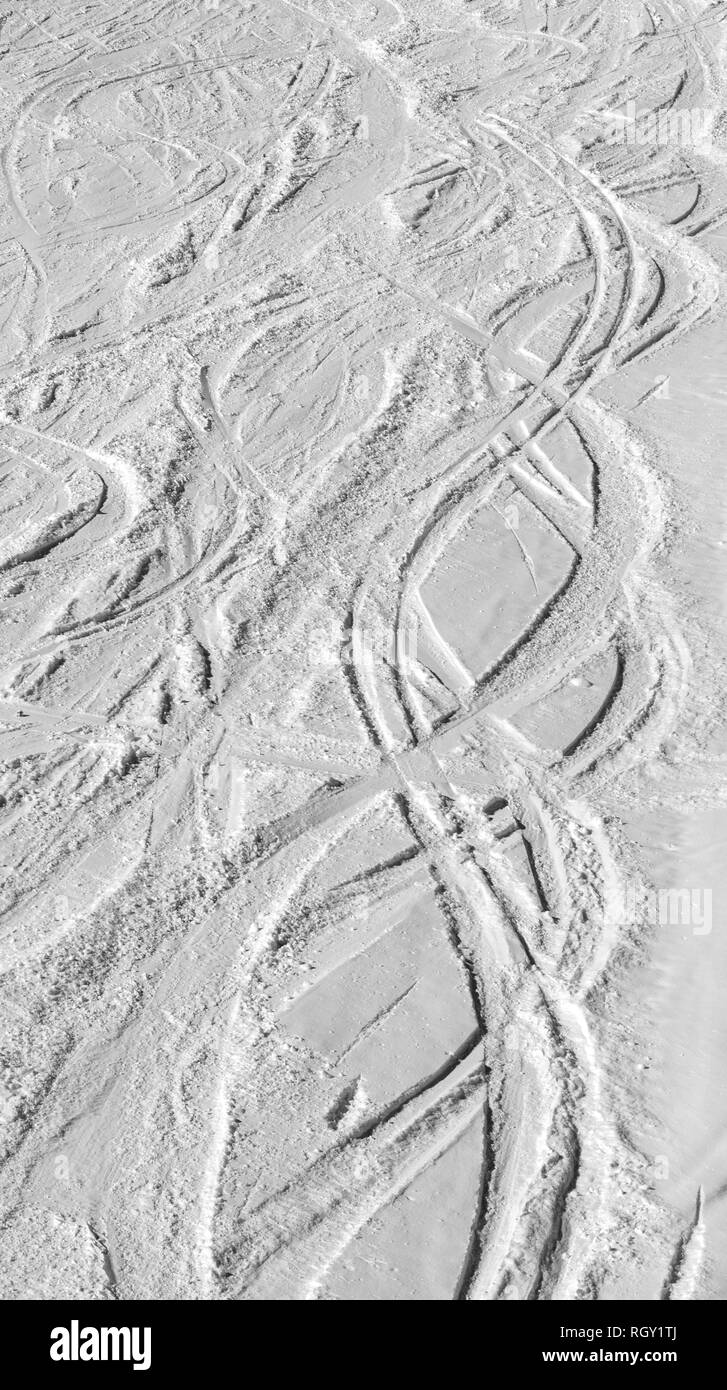 Blanco y negro con nieve ski slope con trazas de esquís y snowboards en el soleado día de invierno Foto de stock