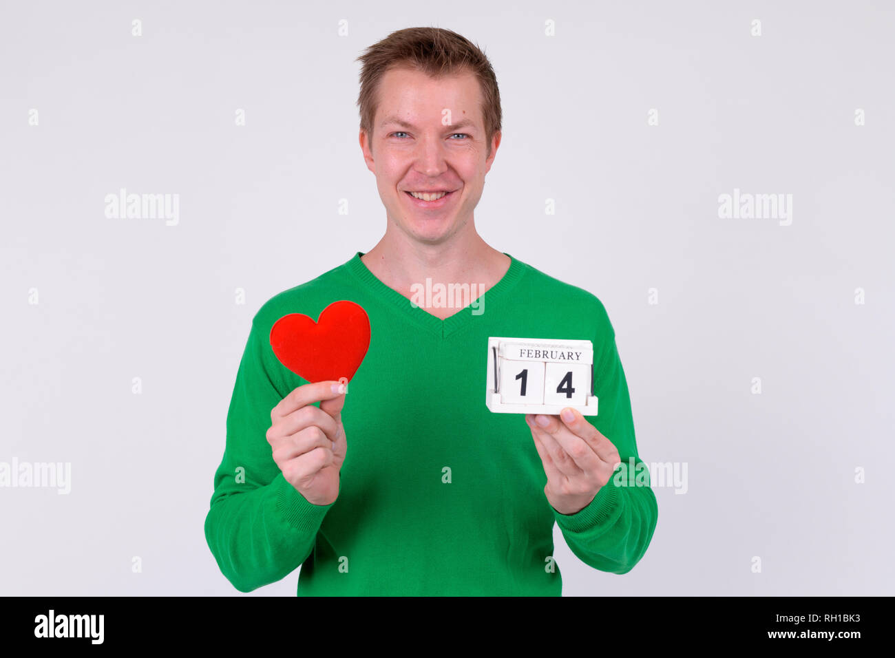 Feliz joven sosteniendo el bloque del calendario y el corazón listo para el día de San Valentín Foto de stock