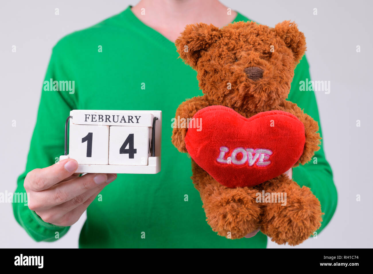 Manos de hombre joven que mantiene el bloque de calendario y oso de peluche listo para el día de San Valentín Foto de stock