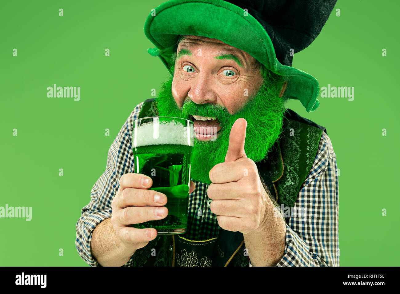 Un sonriente feliz senior hombre en un sombrero de duende con cerveza verde en el studio. Celebra el Día de San Patricio. La celebración, festiva, cerveza, vacaciones, alcohol, parte concepto Foto de stock