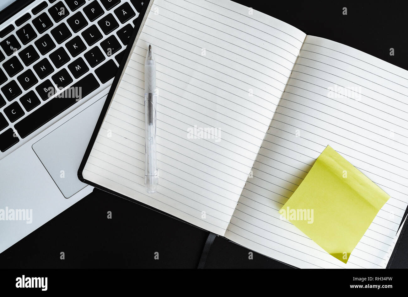 Abrir notas en blanco con nota adhesiva amarilla junto al ordenador portátil Foto de stock