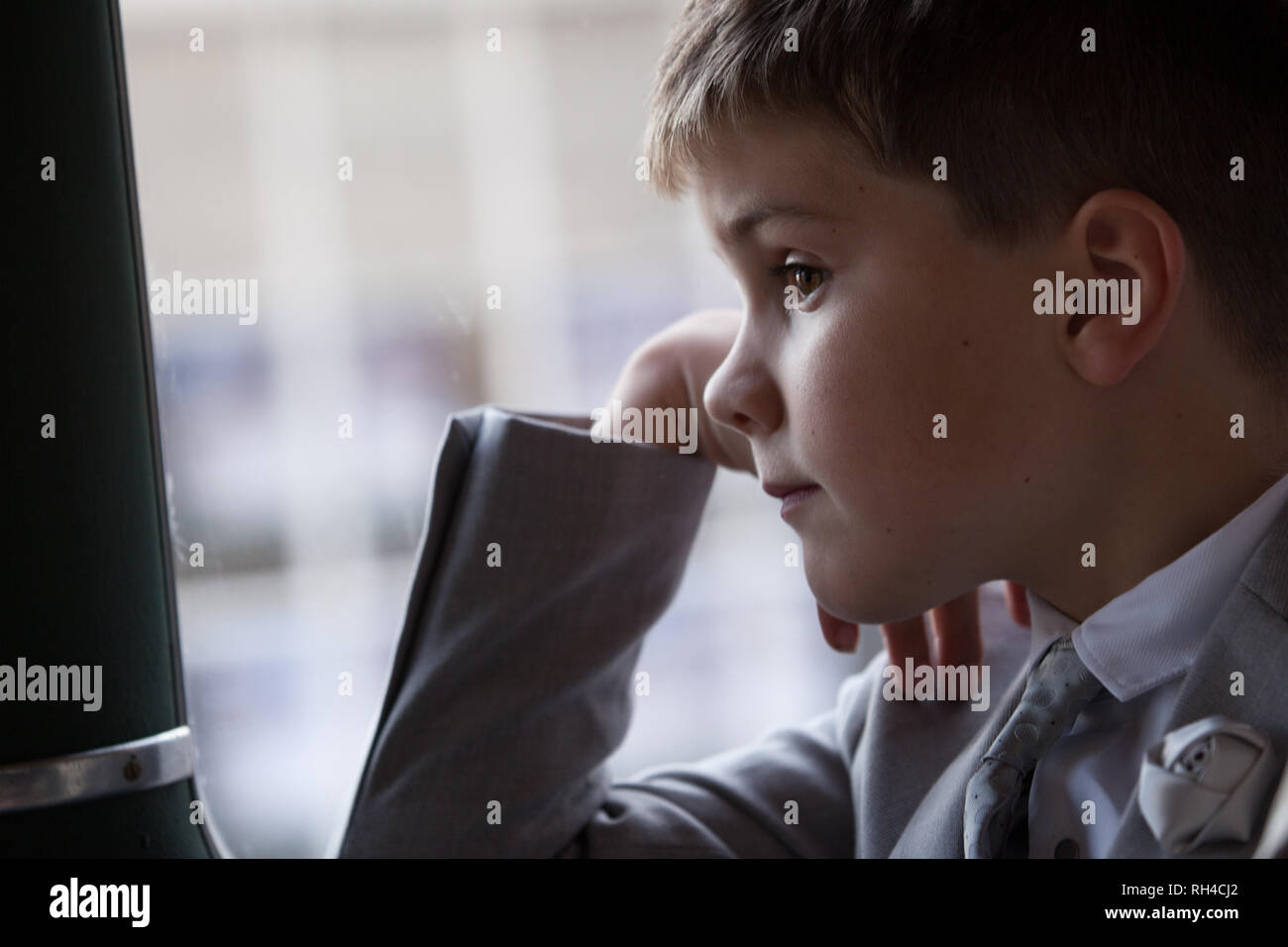 Joven vistiendo suite, con pelo marrón corto mirando por la ventana del vehículo en movimiento. Foto de stock