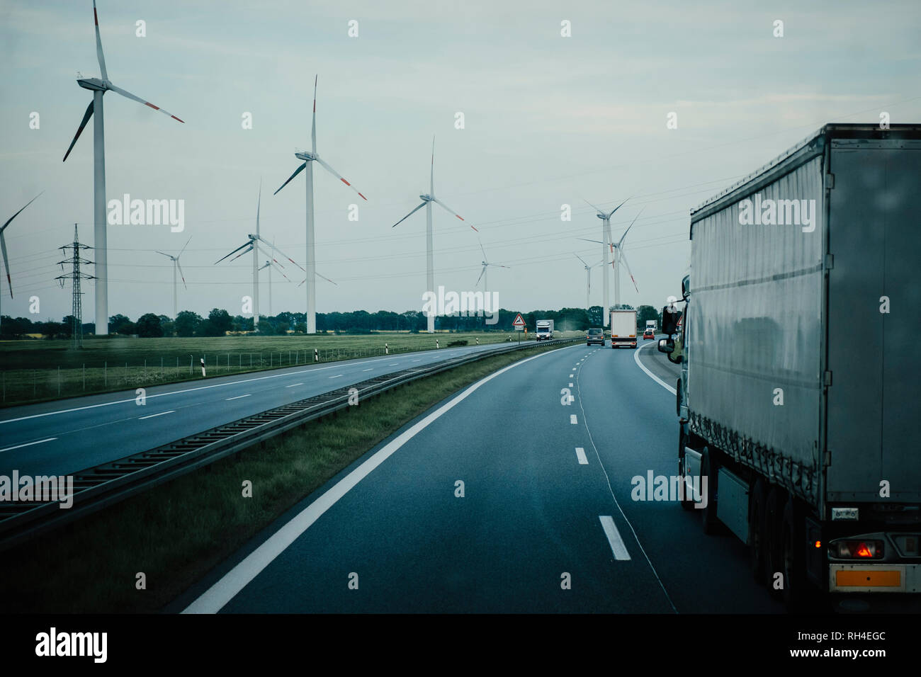 Camiones y coches que se desplazan por carretera a lo largo de las turbinas eólicas, Brandeburgo, Alemania Foto de stock