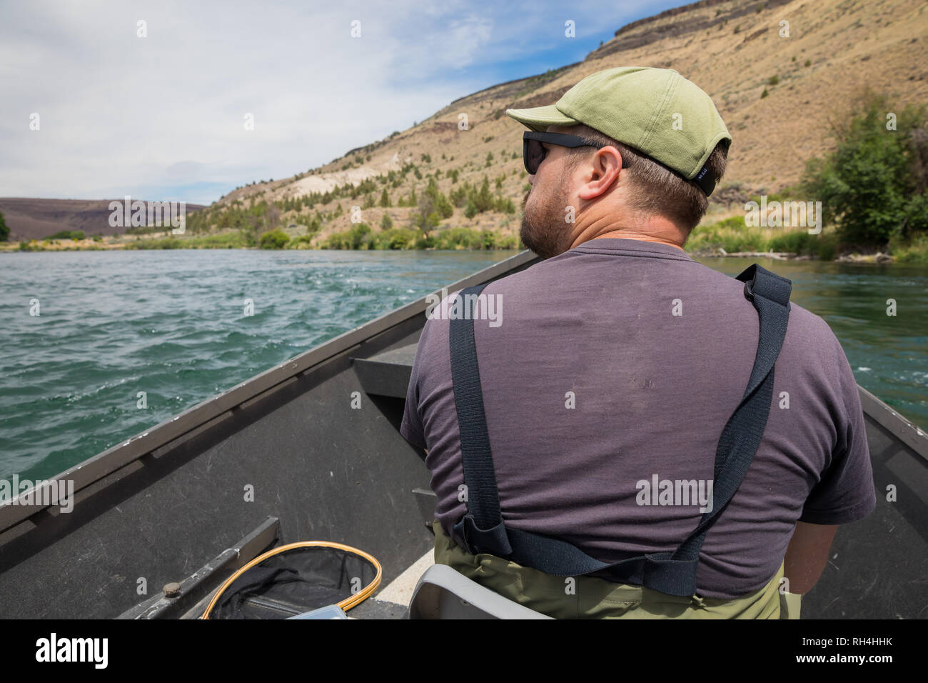 Pescador con mosca sentado en un barco a la deriva mientras está flotando el río para llegar hasta el siguiente acceso a la pesca en el río de Deschutes inferior cerca de Warm Springs Oregon Foto de stock