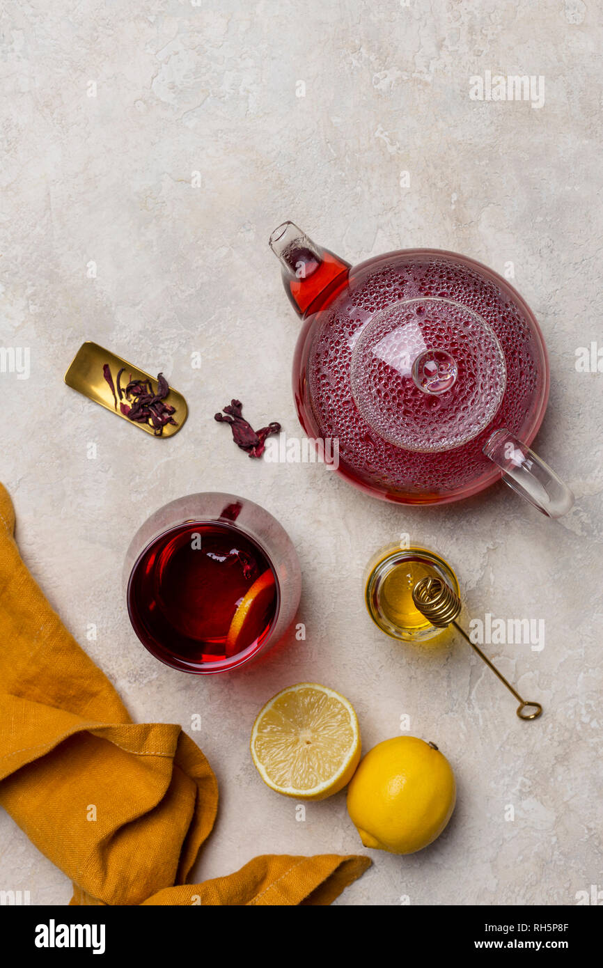 Transparencia copa de té de hibiscus (karkade, agua de flor de Jamaica) con  limón, tetera de cristal, la miel con miel de palo y naranja en la  servilleta blanco volver Fotografía de