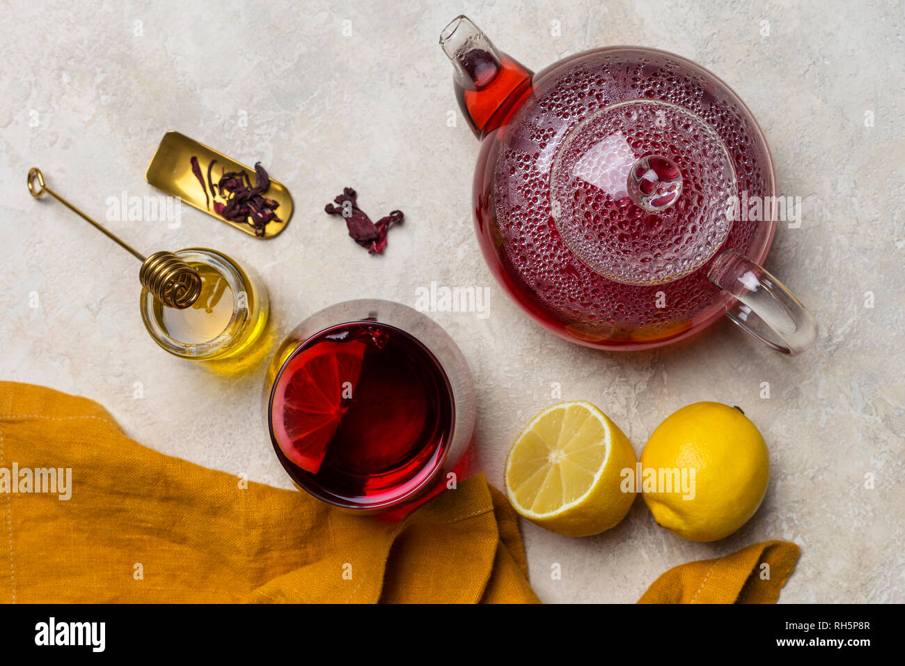 Transparencia copa de té de hibiscus (karkade, agua de flor de Jamaica) con  limón, tetera de cristal, la miel con miel de palo y naranja en la luz de  la servilleta volver