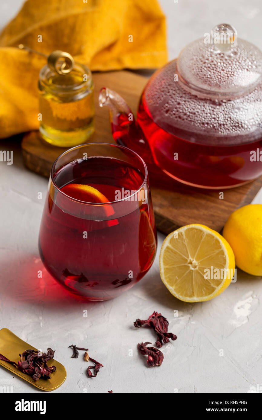 Transparencia copa de té de hibiscus (karkade, agua de flor de Jamaica) con  limón, tetera de cristal, la miel con miel de palo y naranja en la luz de  la servilleta volver