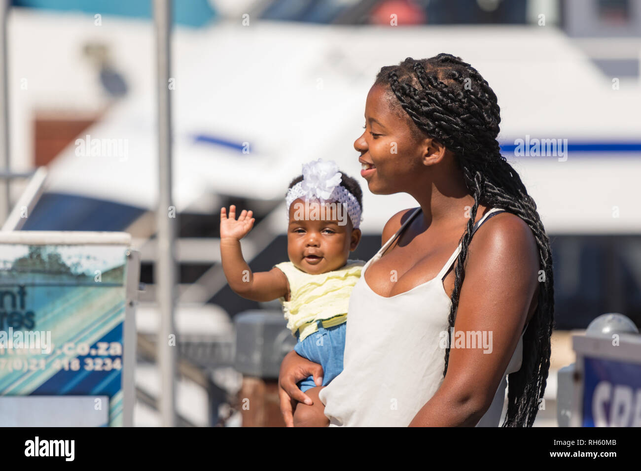 Ciudad del Cabo, Sudáfrica - Enero 2th, 2019: Una joven madre negra  sudafricana con su bebé en brazos diciendo hola en el Cape Town Waterfront  Fotografía de stock - Alamy