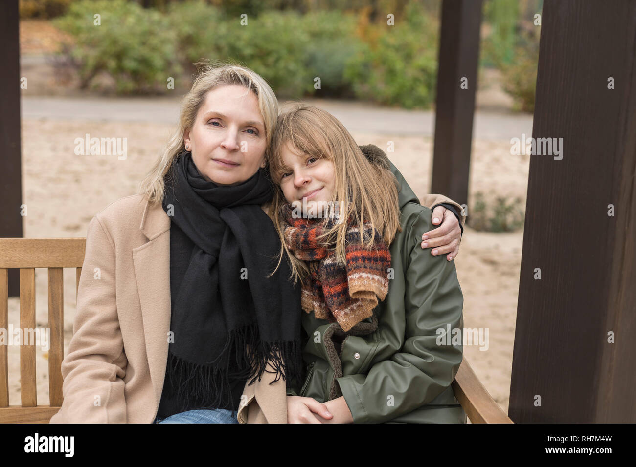 Retrato cariñosa madre e hija abrazando en banco del parque Foto de stock