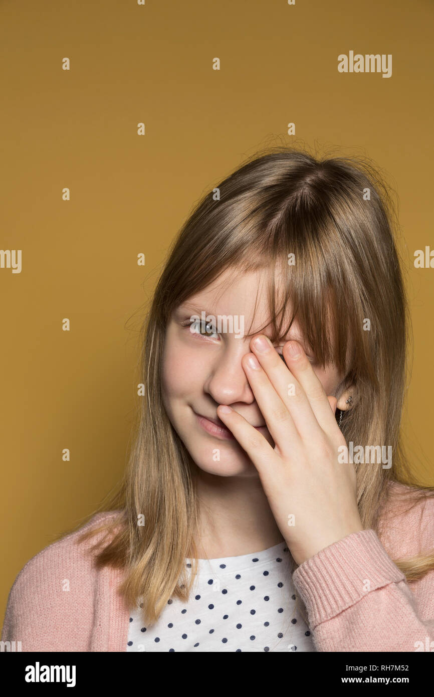 Retrato sonriente chica de interpolación cubriendo ojo con la mano Foto de stock