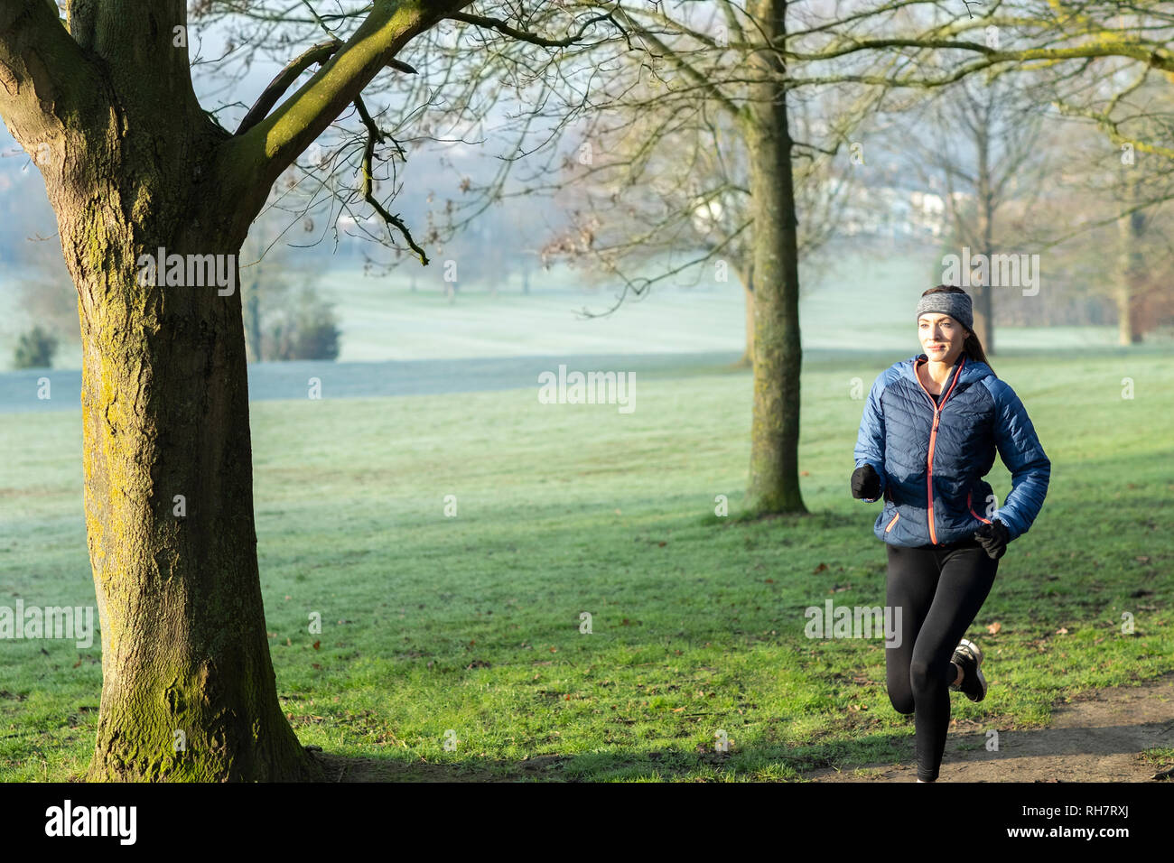 Mujer en invierno a primera hora de la mañana recorren Park mantenerse en forma haciendo ejercicio Foto de stock