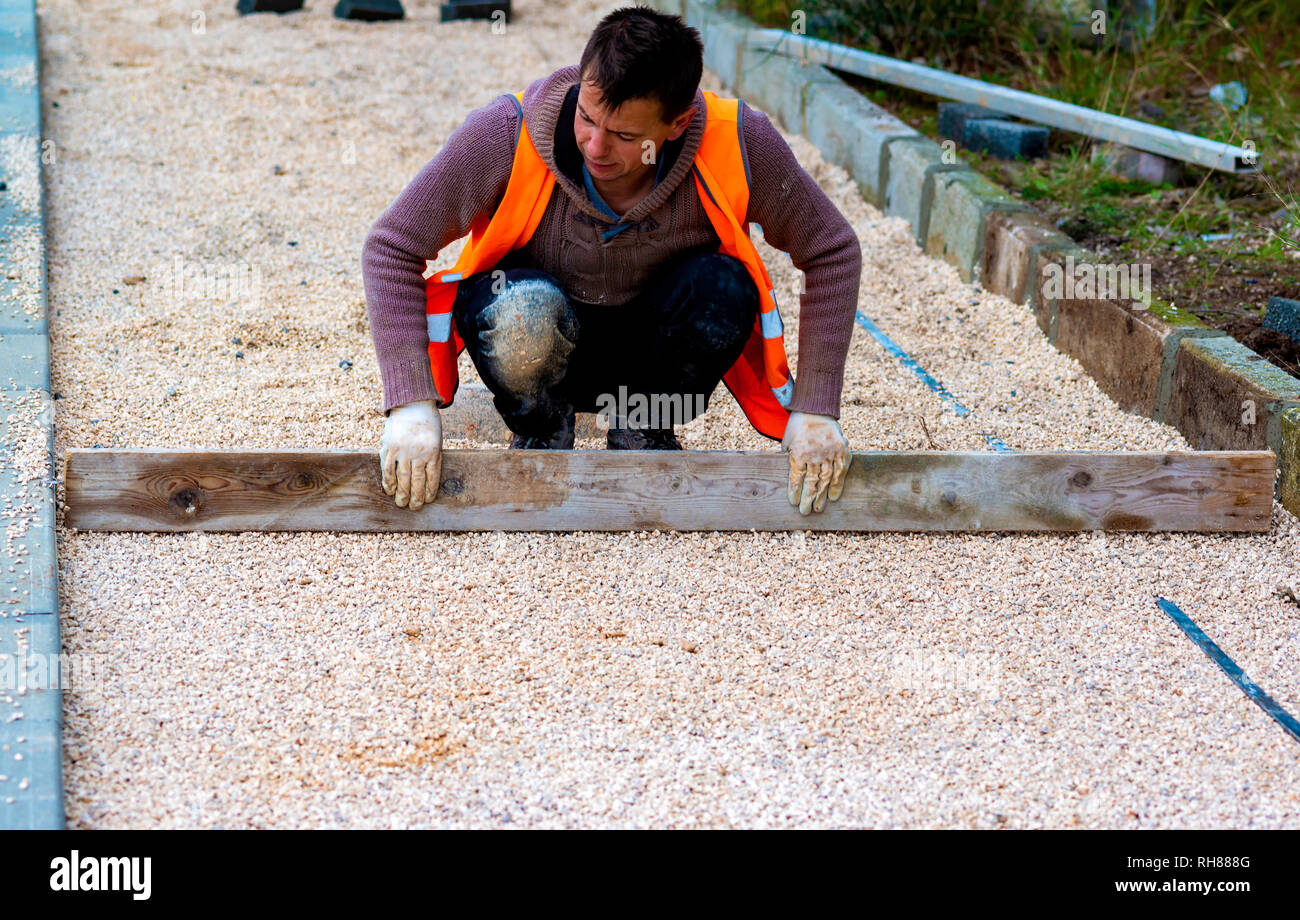 Trabajador de la construcción de pavimentos de hormigón Colocación  entrelazados en hoja de cama no tejidas arena y colocarlos en su lugar  Fotografía de stock - Alamy