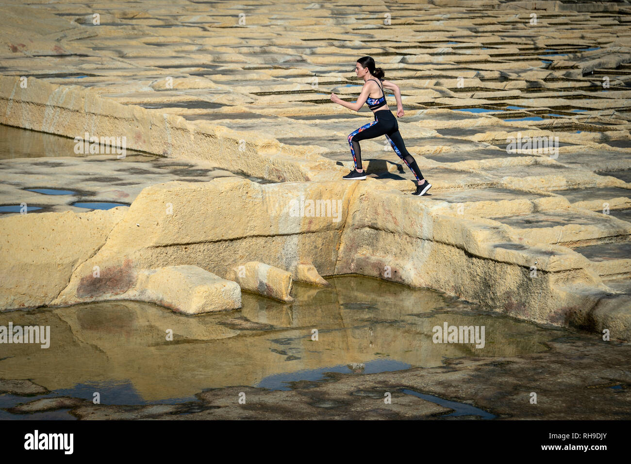 Mujer runner, corriendo a través de la caliza salinas en Malta. Foto de stock