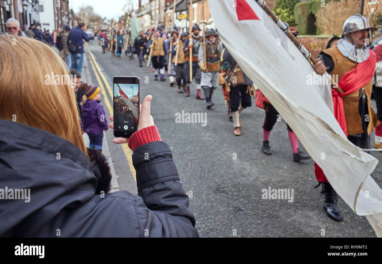 Una mujer videoing en modo vertical en una cámara de teléfono la marcha hacia abajo por la fila galés nudo sellado en el 2019 Batalla de Nantwich Foto de stock
