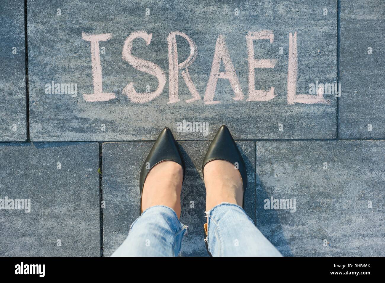 Vista desde arriba, los pies femeninos con texto escrito en Israel acera gris Foto de stock