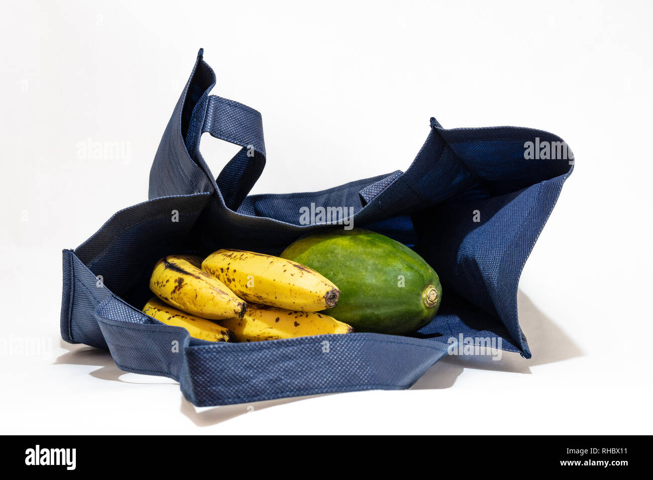 Compras reutilizable/ bolsa de ultramarinos con frutas aisladas sobre fondo blanco. Foto de stock