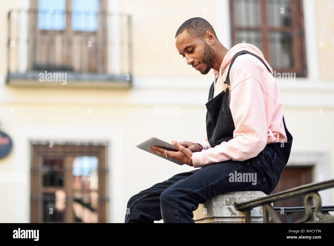 Joven negro mediante tableta digital en el contexto urbano. Foto de stock