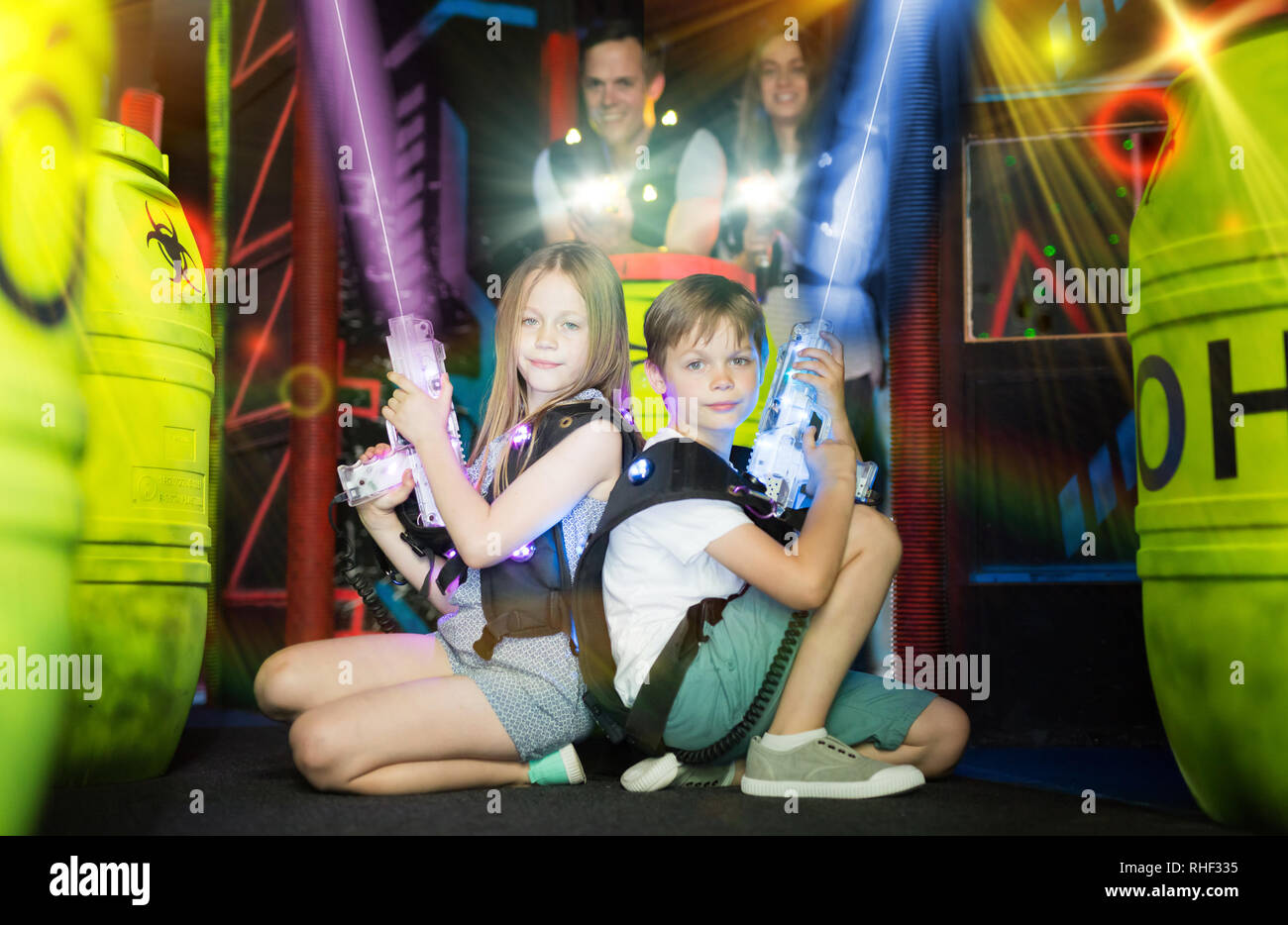 Dos poco confiado laser tag jugadores sentados espalda con espalda con  pistolas en el terreno de juego en rayos luminosos de pistola láser  Fotografía de stock - Alamy