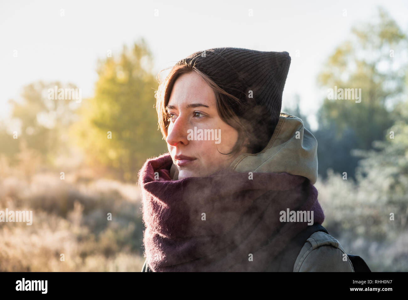 Contraluz retrato de hermosa mujer empañado la respiración. Persona de sexo femenino, paseos al aire libre en la fría y soleada mañana de otoño Foto de stock