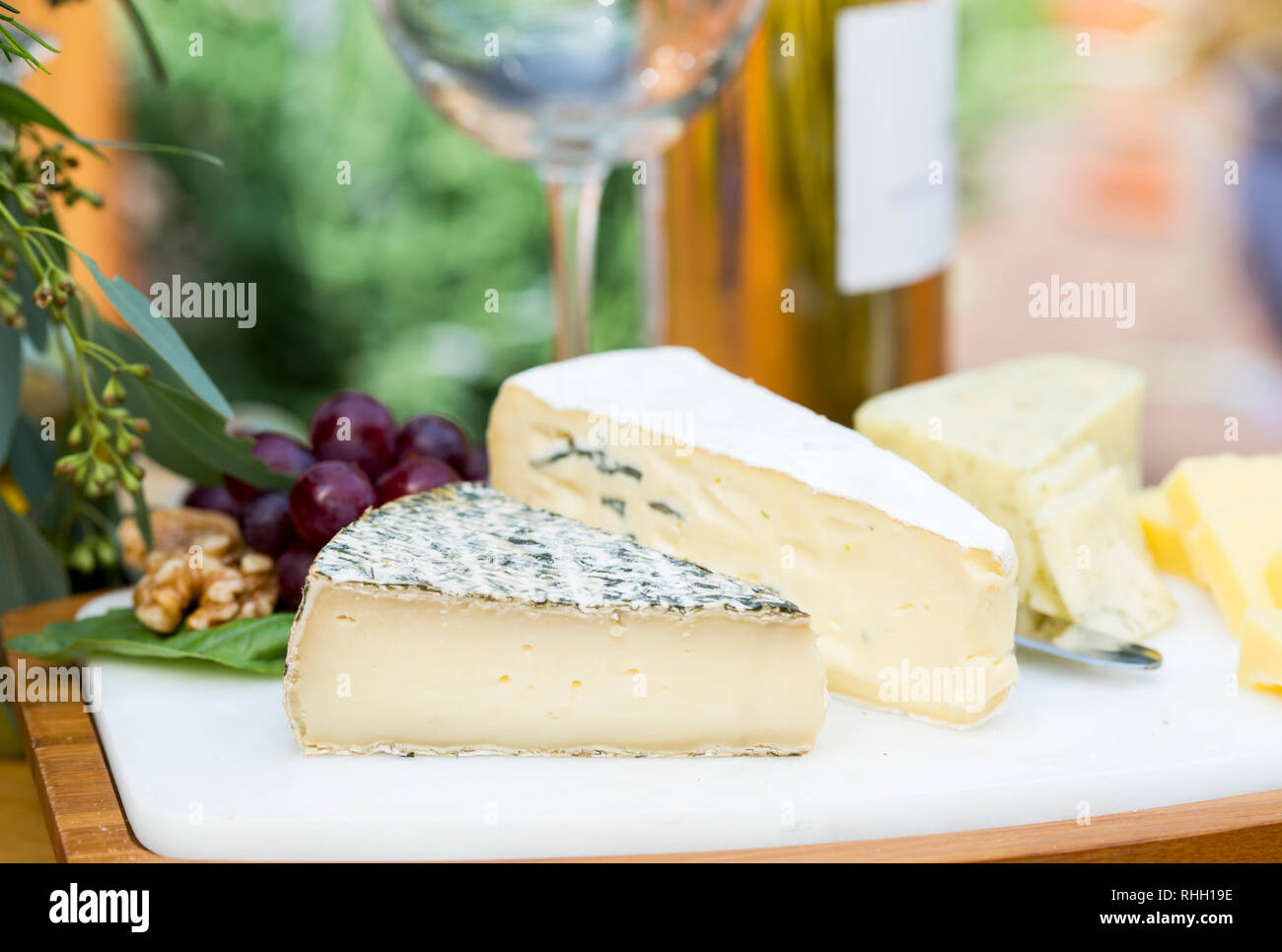 Tres grandes porciones de queso sobre una tabla de quesos de mármol- al aire libre entretenido. Foto de stock
