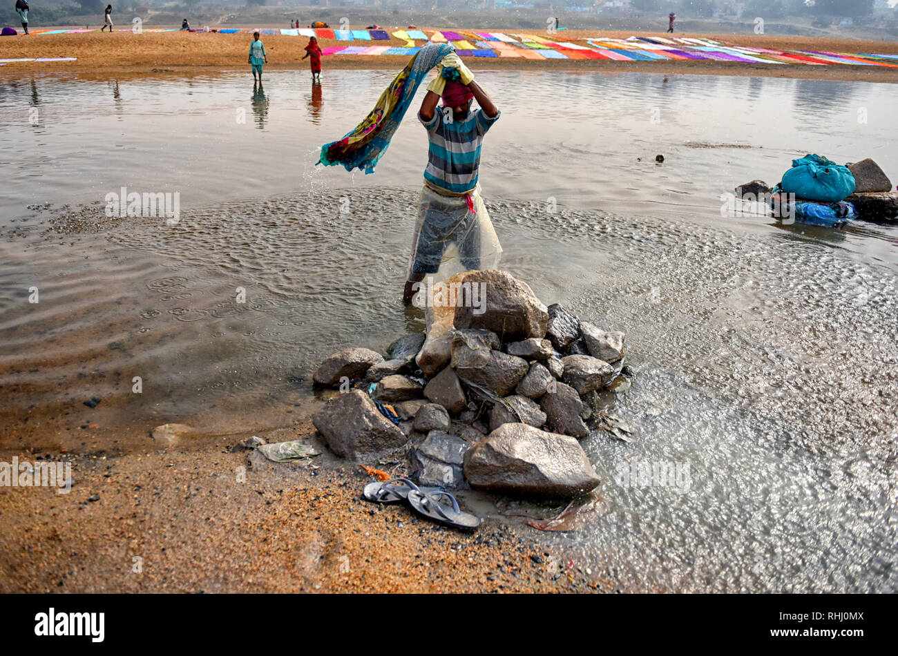 Dhobi visto lavando la ropa en el río Barakar en la parte oriental de la India antes de repartirlas en el suelo junto a la orilla del río de Barakar en Jharkhand área. El Dhobi Ghat (lavado) de tierra en la provincia de Jharkhand Kumardubi es el más grande en el mundo. Foto de stock