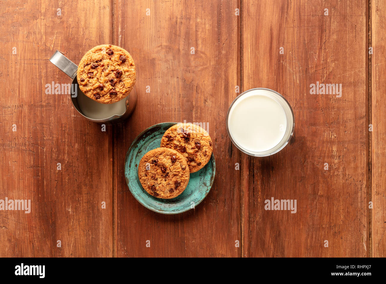 Una fotografía aérea de galletas de chocolate oscuro sobre un fondo de madera rústica con leche y copie el espacio Foto de stock