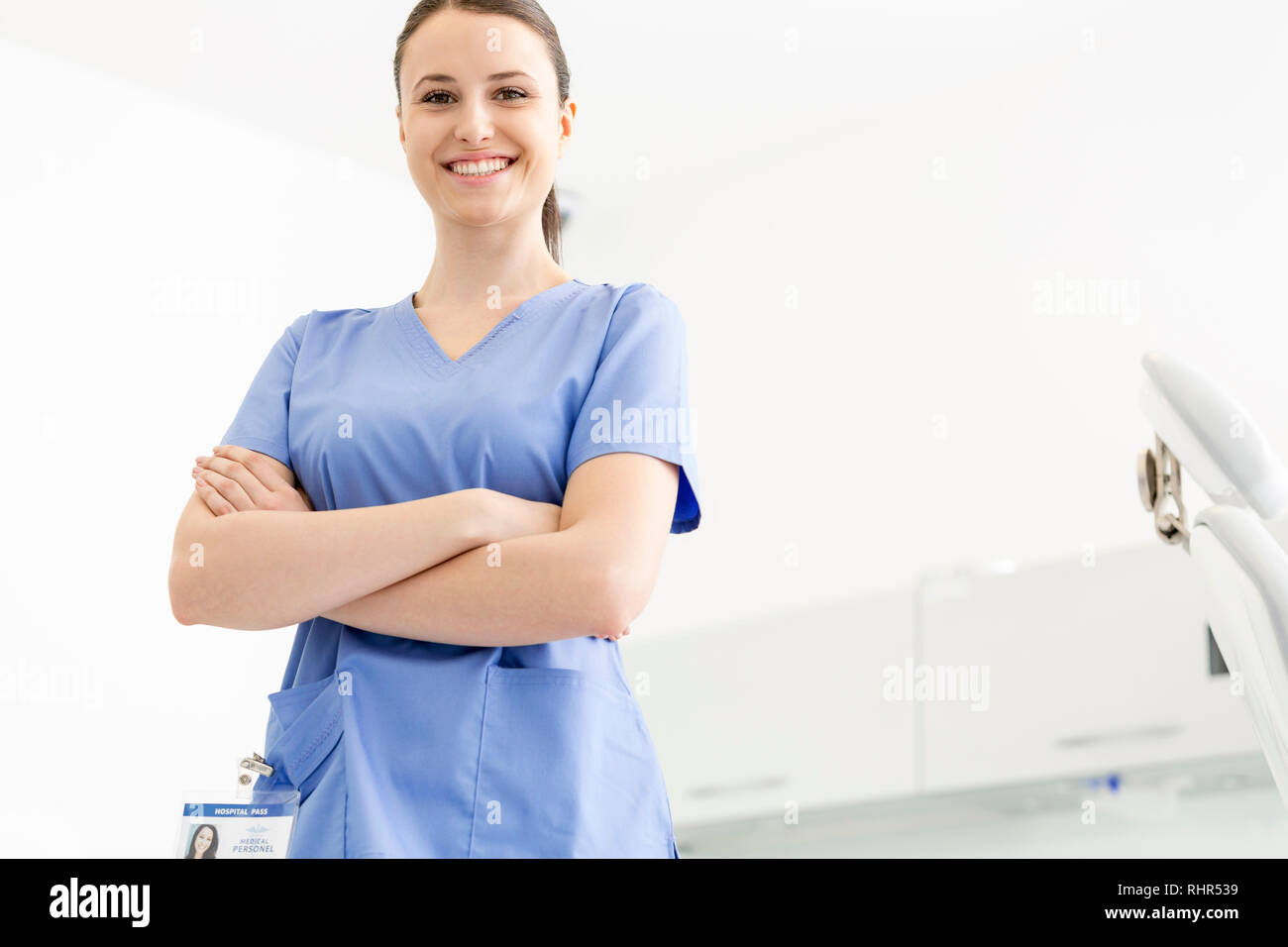 Retrato de seguros sonriente enfermera con los brazos cruzados en la clínica Foto de stock