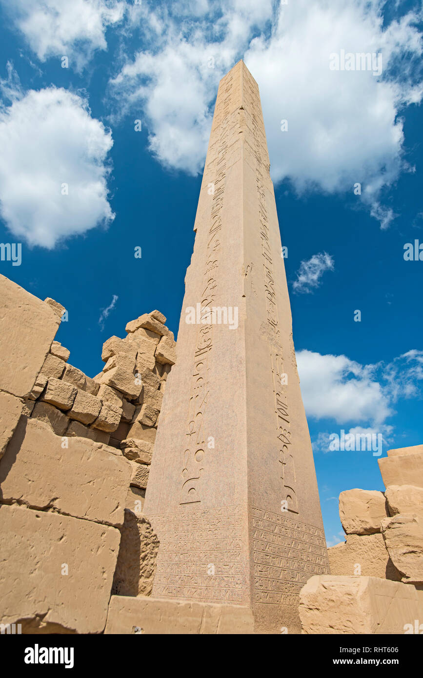 Gran tall antiguo obelisco egipcio en el templo de Karnak, en Luxor, con tallas de jeroglíficos sobre fondo de cielo azul Foto de stock