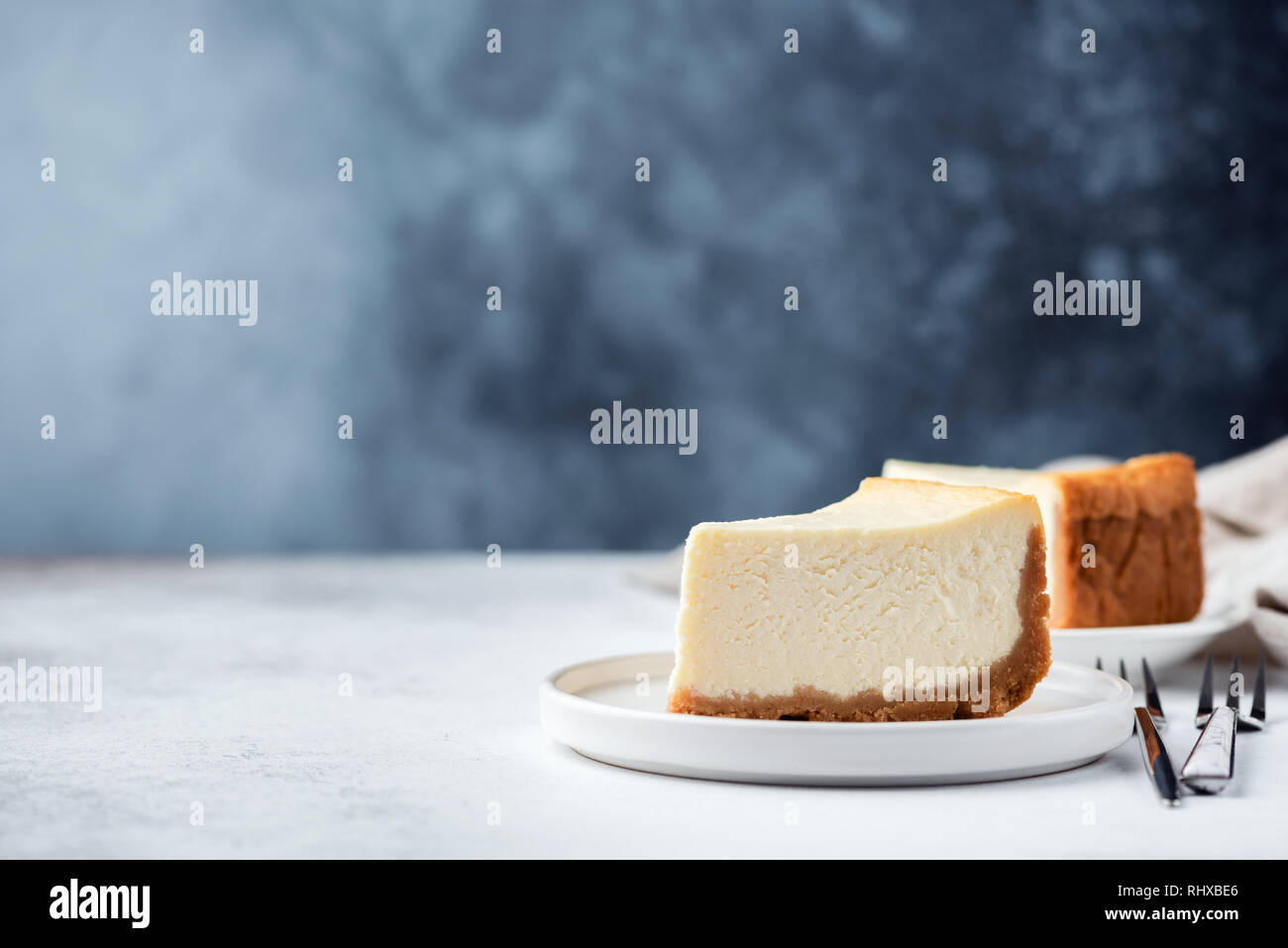 Llanura clásico Nueva York Cheesecake sobre azul de fondo concreta. Espacio para el texto copia Foto de stock