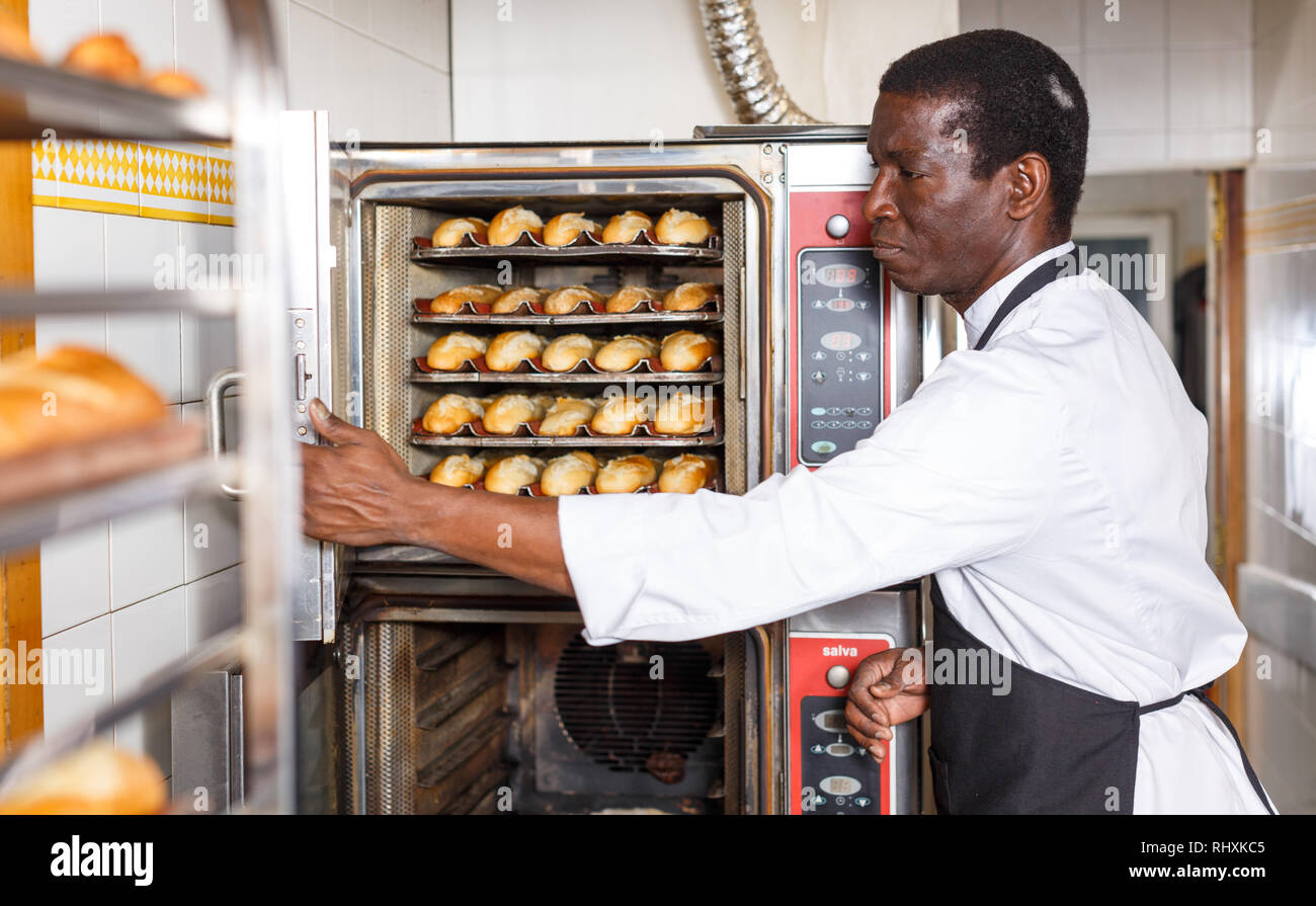 Retrato del afroamericano Baker, control de proceso de hornear pan en horno  profesional en la panadería Fotografía de stock - Alamy
