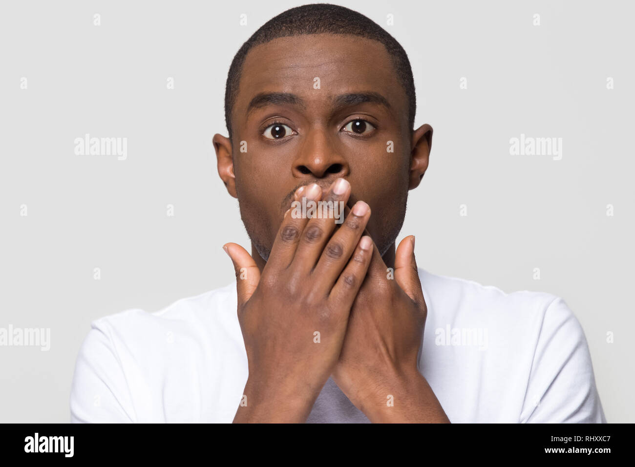 Conmocionado horrorizado hombre africano cubriendo la boca con las manos sientes miedo Foto de stock
