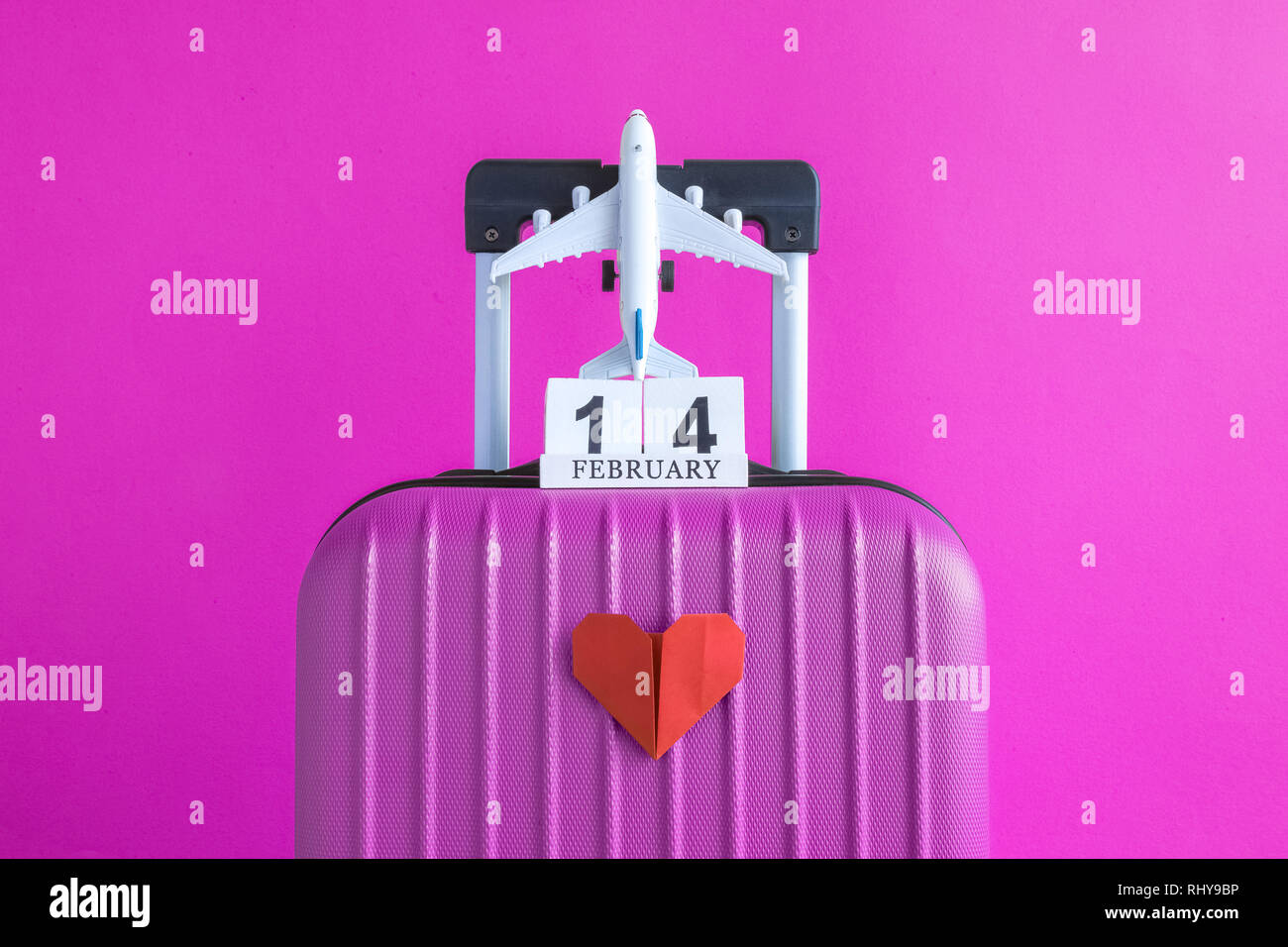 Maleta con 14 de febrero calendario de madera y el modelo de avión de  juguete con origami corazón rojo sobre fondo de color rosa viaje creativo  concepto minimalista Fotografía de stock - Alamy