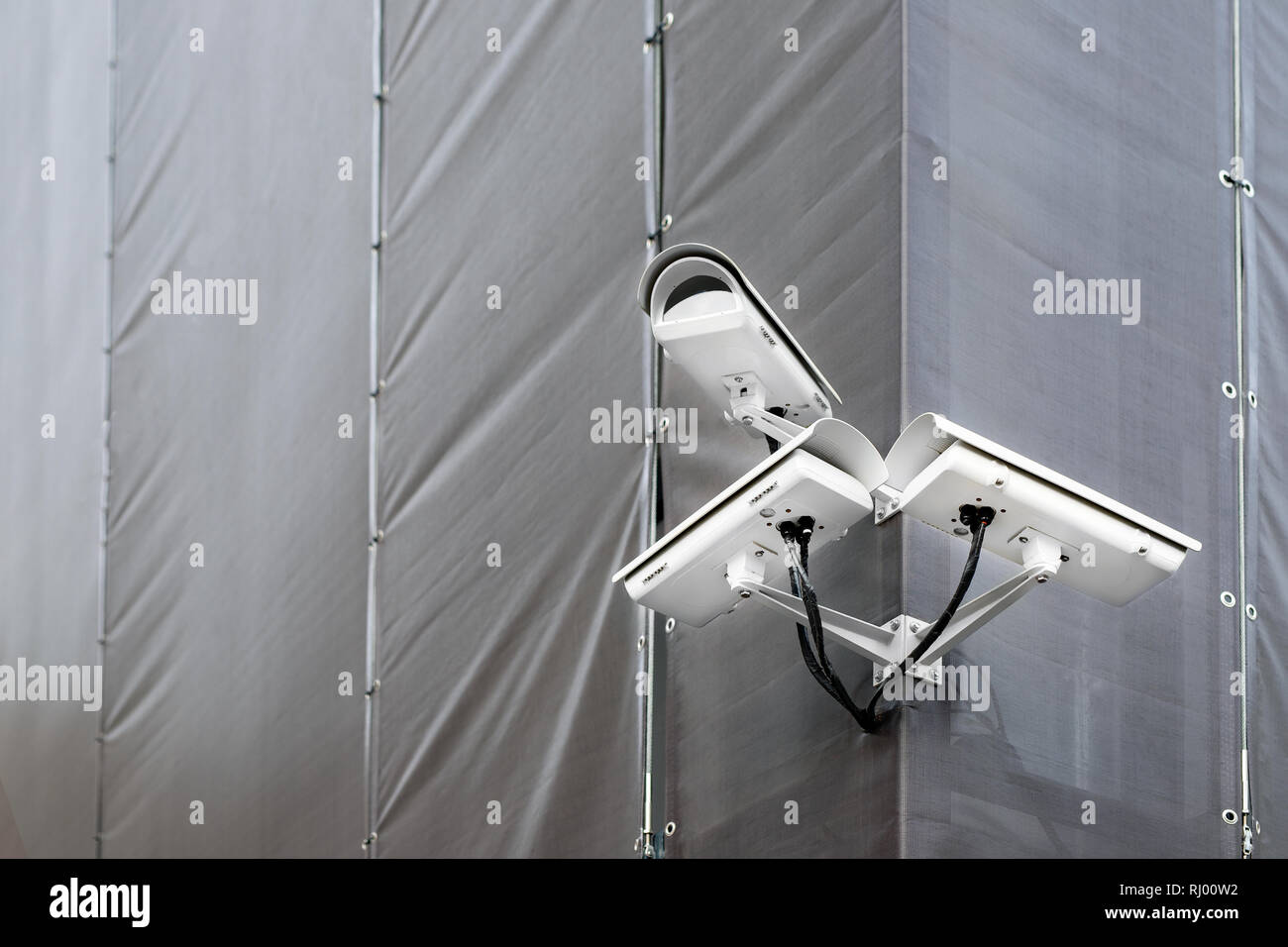 Tres cámaras CCTV en la esquina del edificio en restauración o renovación exterior. Cámaras de seguridad en el muro de la construcción en las calles de la ciudad Foto de stock