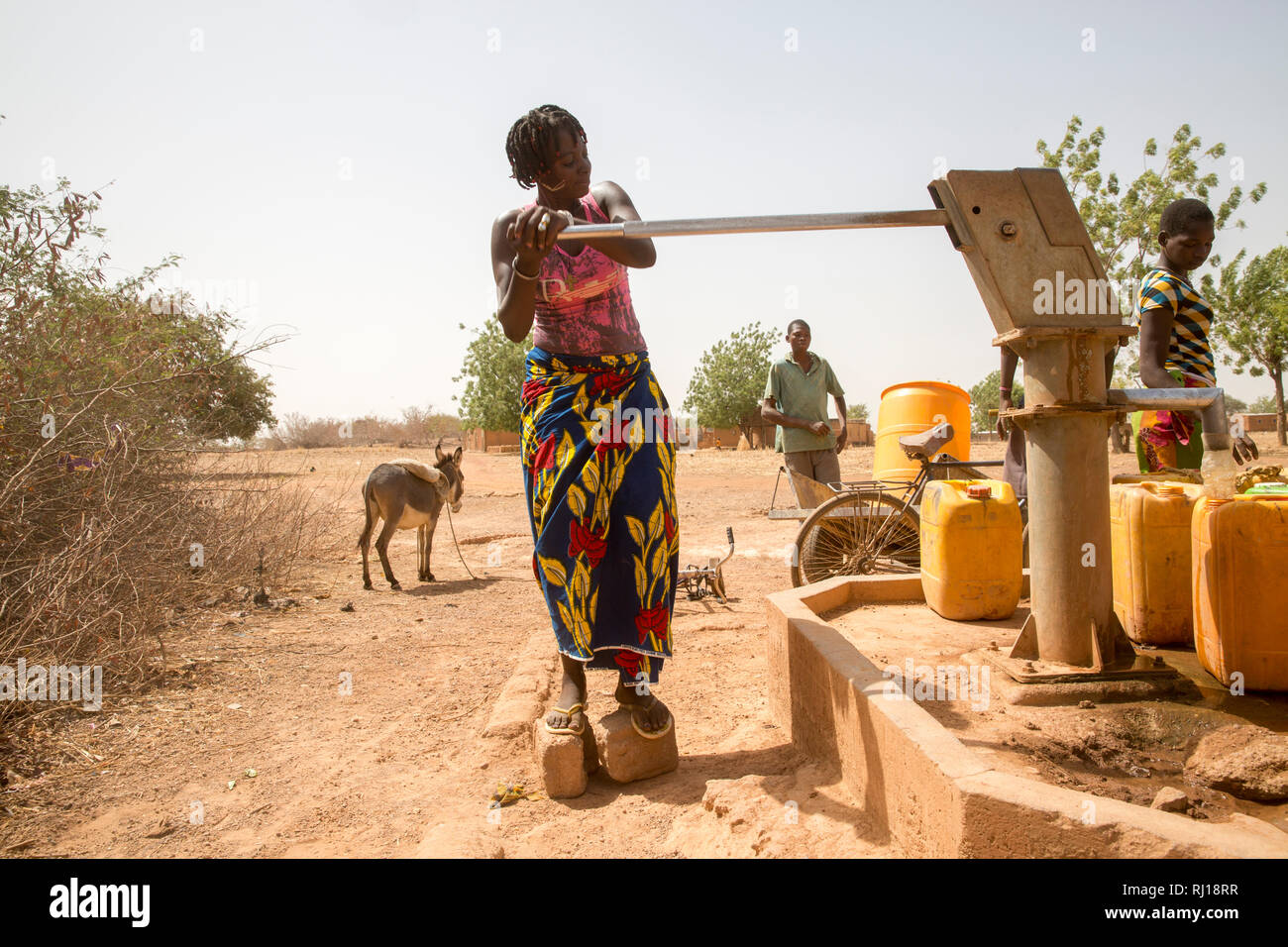 Aldea de Samba, Provincia Yako, Burkina Faso; Salamata Zoundi, 27, va a recoger el agua de la bomba cercana con sus trillizos, Christelle, Christine y Christophe, de 2 años Foto de stock