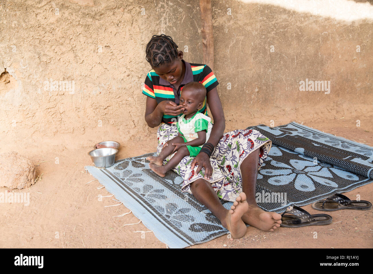 Aldea de Samba, Provincia Yako, Burkina Faso: Abzetta Sondo, de 19 años, y su hijo Noel Nougtara, 15 meses. Su bebé padece malnutrición aguda. Foto de stock