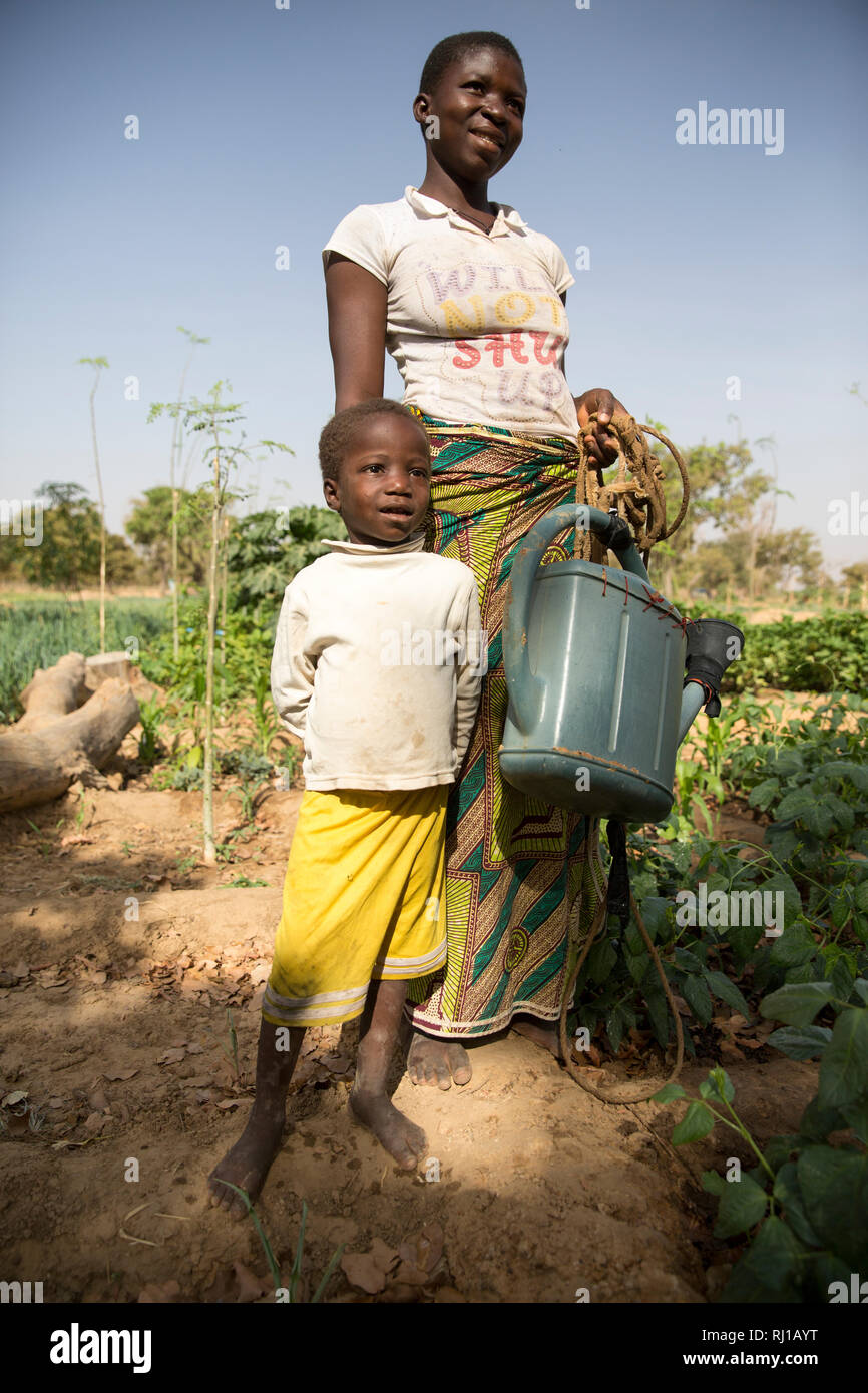 Aldea de Samba, Provincia Yako, Burkina Faso: Collette Guiguemde, de 26 años, con sus cuatro años de edad, hija Eulalie Zondi en la huerta. Foto de stock