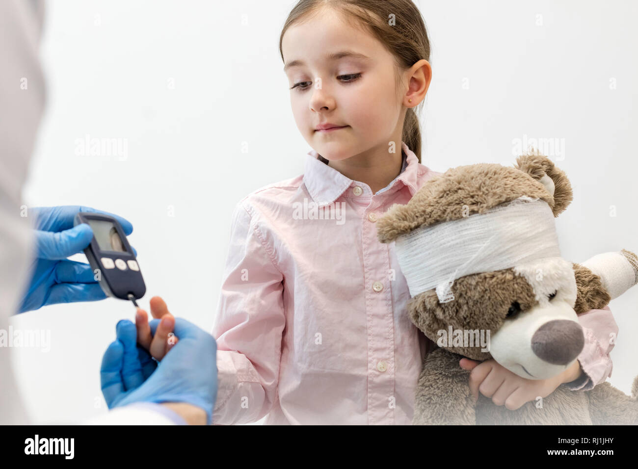 Control médico diabéticos en el equipo de chica con osito de peluche en la clínica Foto de stock