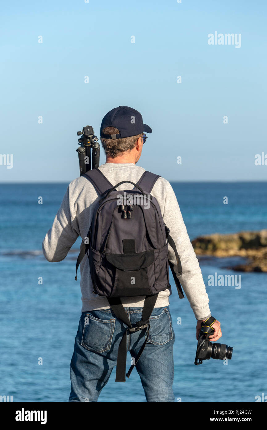 Vista posterior de un fotógrafo llevar un trípode y cámara, mirando al mar  Fotografía de stock - Alamy